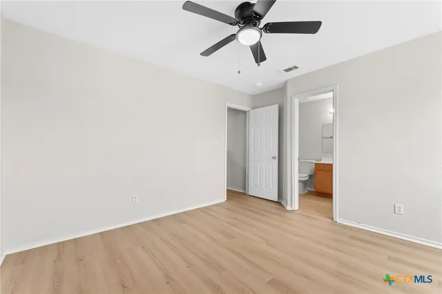 an empty room with wooden floor and ceiling fan