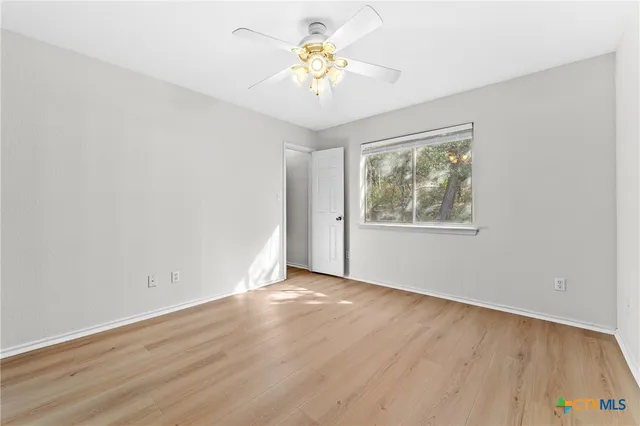a view of an empty room with window and wooden floor