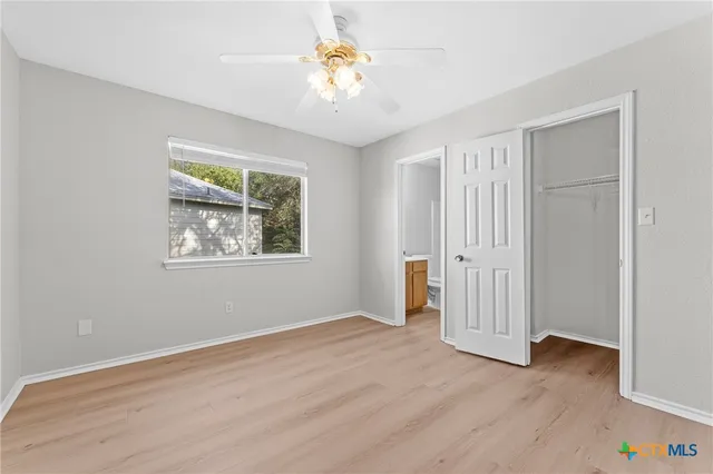 a view of an empty room with window and wooden floor