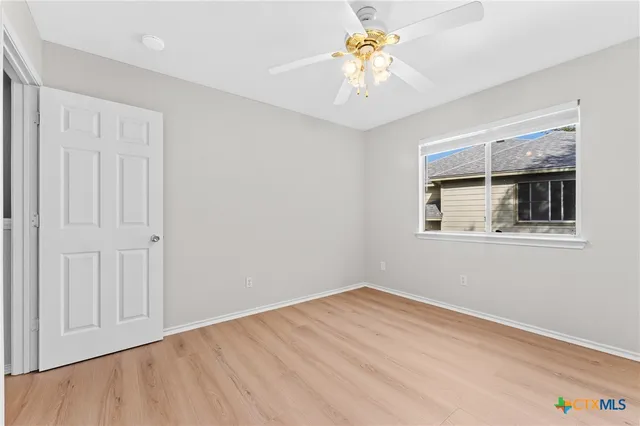 a view of empty room with wooden floor and fan
