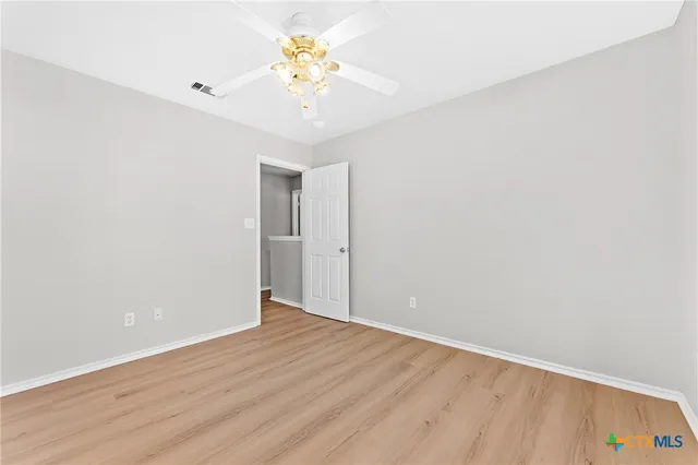 an empty room with wooden floor and chandelier fan