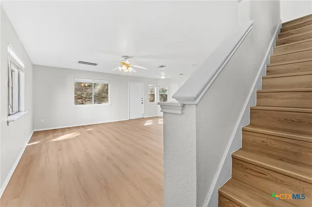 a view of an empty room with wooden floor and stairs