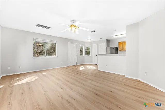 a view of empty room with wooden floor and fan