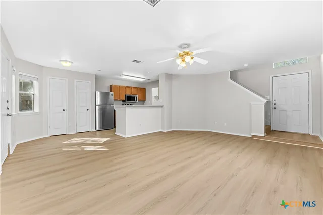 an empty room with wooden floor and natural light