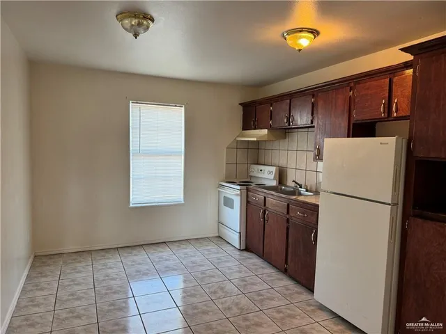 a kitchen with a refrigerator a stove top oven and cabinets