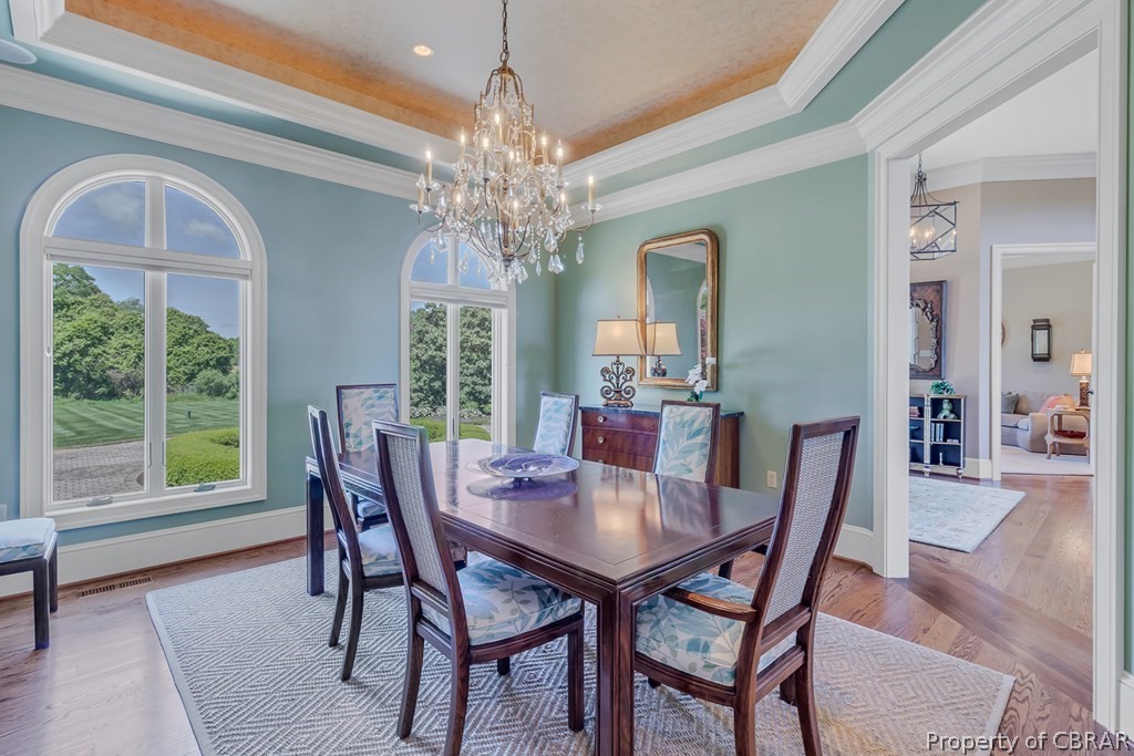 2055 Ditchley Road Kilmarnock, VA 22482 - Photo 13 of 48 Dining space featuring plenty of natural light, an inviting chandelier, wood-type flooring, and a raised ceiling