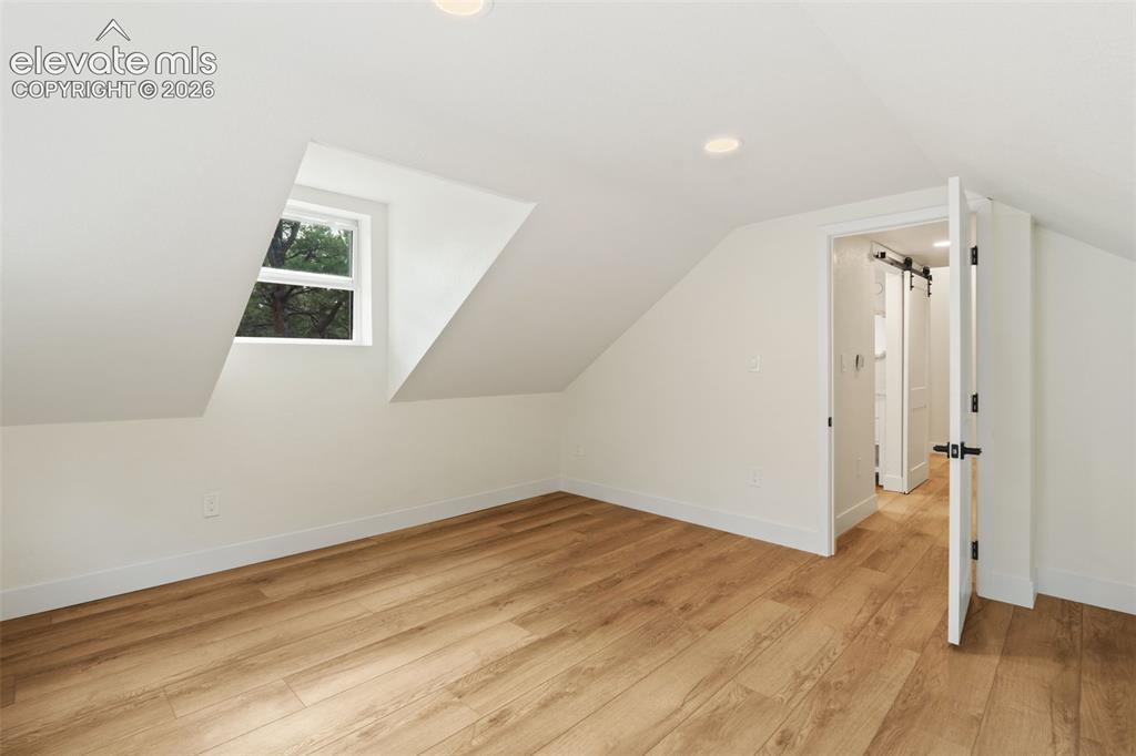 11665 Greentree Road Colorado Springs, CO 80908 - Photo 26 of 43 Bonus room with light wood-style flooring, recessed lighting, vaulted ceiling, and a barn door