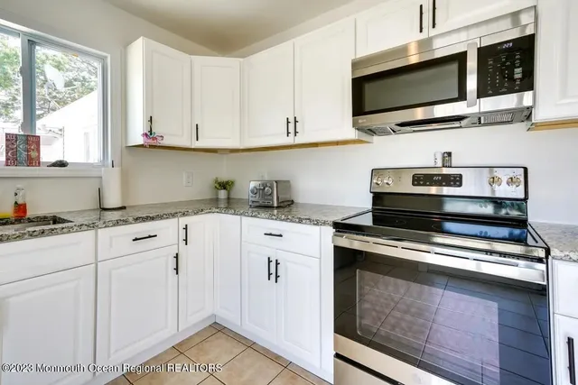 a kitchen with stainless steel appliances white cabinets and a stove top oven