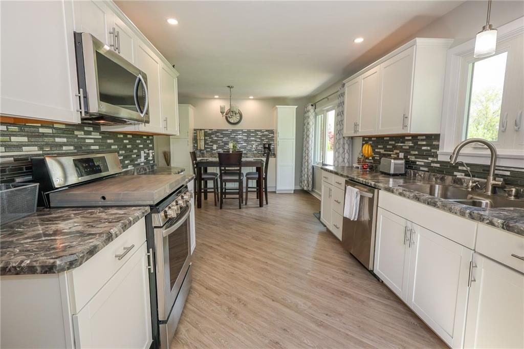 3689 Ridgewood Drive Hermitage, PA 16148 - Photo 8 of 49 a kitchen with stainless steel appliances granite countertop a stove top oven a sink a dining table and chairs with wooden floor