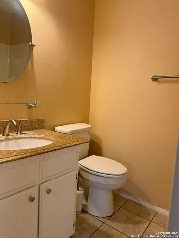 a bathroom with a granite countertop toilet and a sink