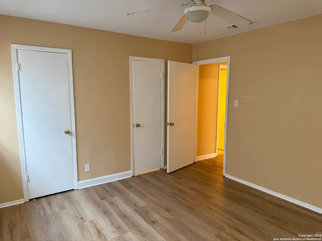 an empty room with wooden floor and a ceiling fan