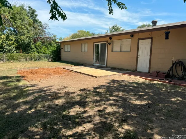 a backyard of a house with large trees and wooden fence