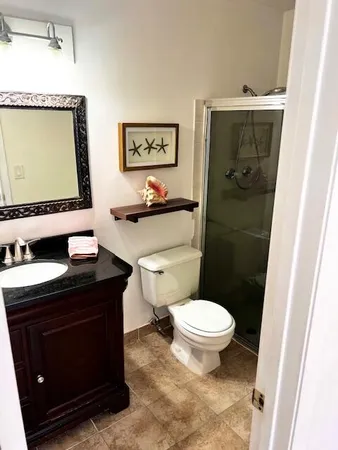 a bathroom with a granite countertop toilet sink and mirror