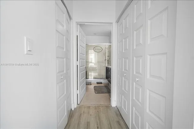 a view of a hallway with wooden floor and a bathroom