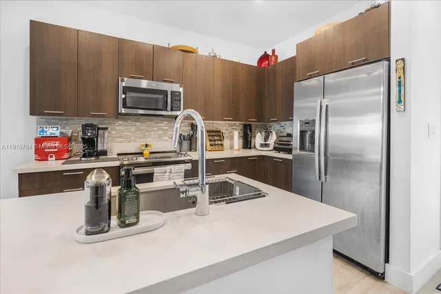 a kitchen with a refrigerator a microwave a sink and cabinets