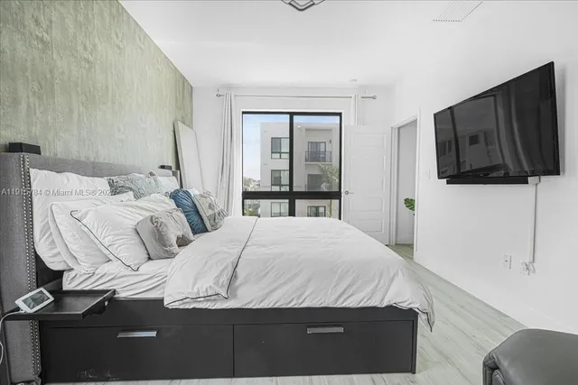 a bedroom with a bed a flat screen tv and guitar