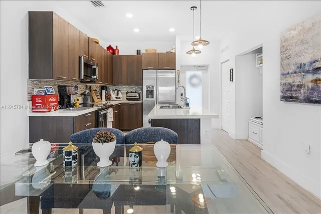 a kitchen with stainless steel appliances kitchen island granite countertop a refrigerator and a wooden cabinets