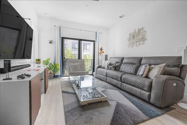 a living room with furniture a flat screen tv and a window
