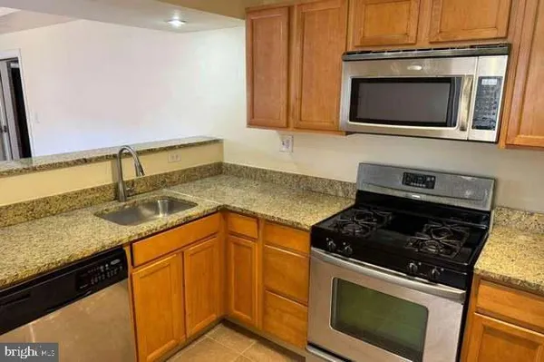 a kitchen with granite countertop stainless steel appliances a stove a sink and a microwave