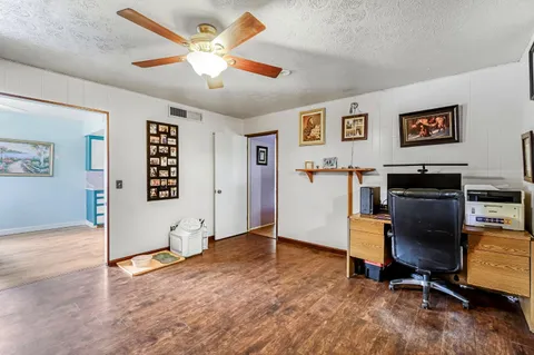 a view of a livingroom with a fireplace a ceiling fan a fireplace a ceiling fan and a refrigerator