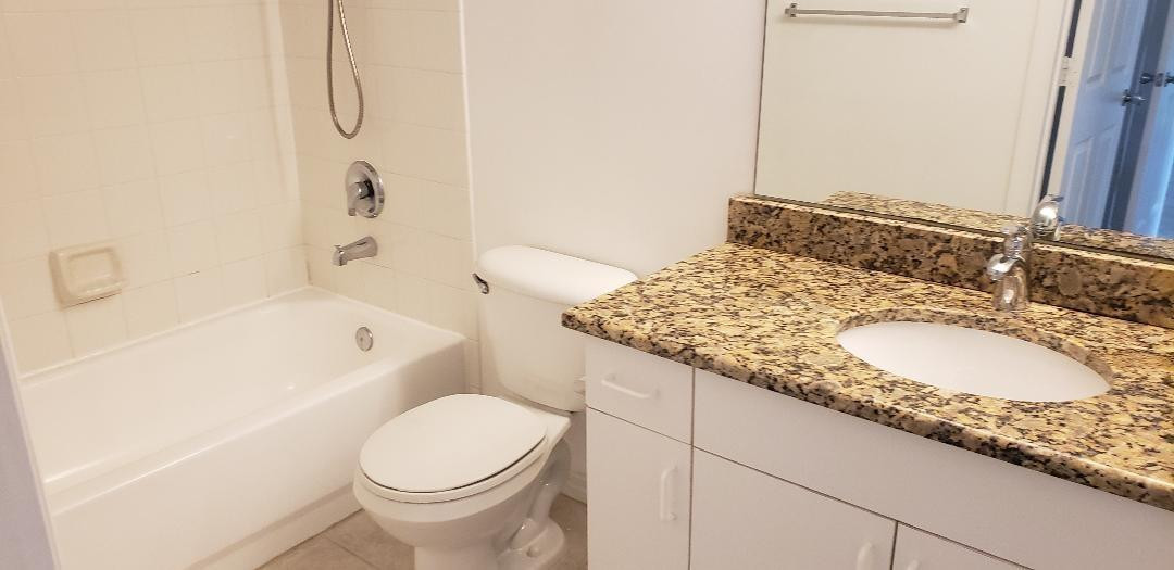 5011 Wiles Road, Unit 301 Coconut Creek, FL 33073 - Photo 12 of 16 a bathroom with a granite countertop sink and a mirror