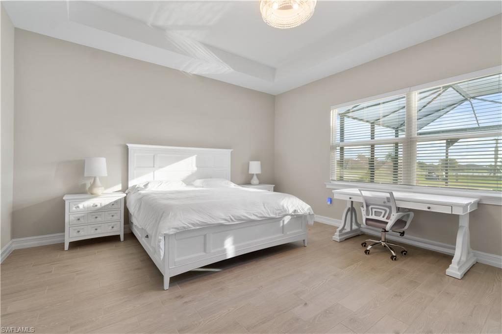 18684 Ensenada Drive Naples, FL 34114 - Photo 14 of 34 a bedroom with a bed a table and large window