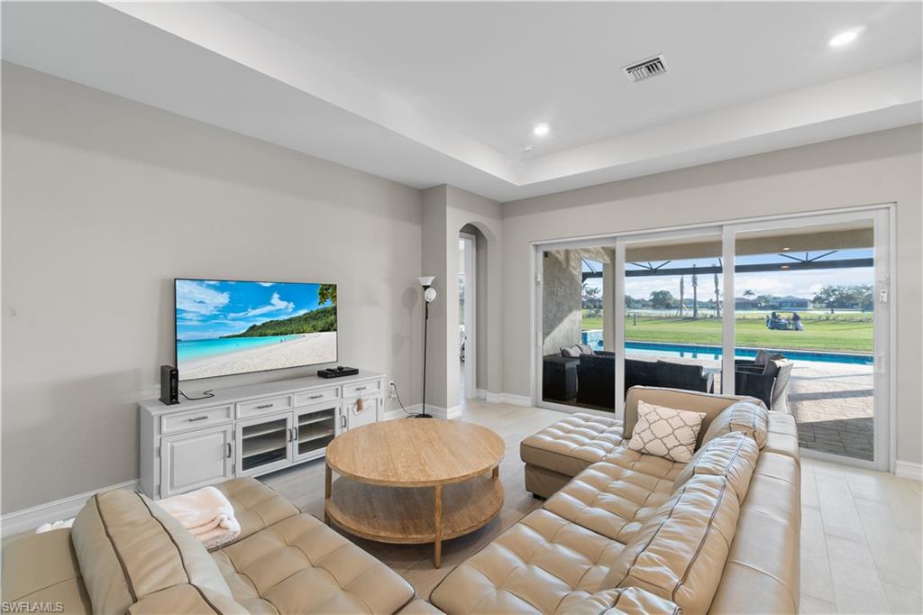 18684 Ensenada Drive Naples, FL 34114 - Photo 3 of 34 a living room with furniture a flat screen tv and a floor to ceiling window
