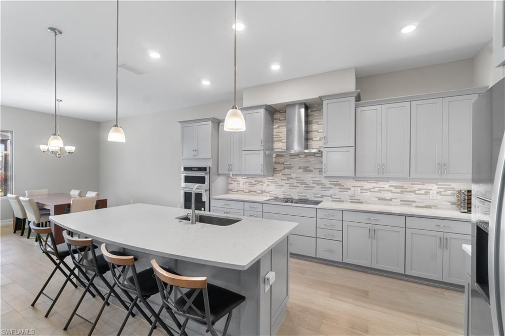 18684 Ensenada Drive Naples, FL 34114 - Photo 7 of 34 a kitchen with a dining table chairs sink and cabinets