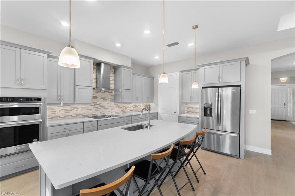 18684 Ensenada Drive Naples, FL 34114 - Photo 8 of 34 a kitchen with kitchen island a refrigerator stove microwave and cabinets