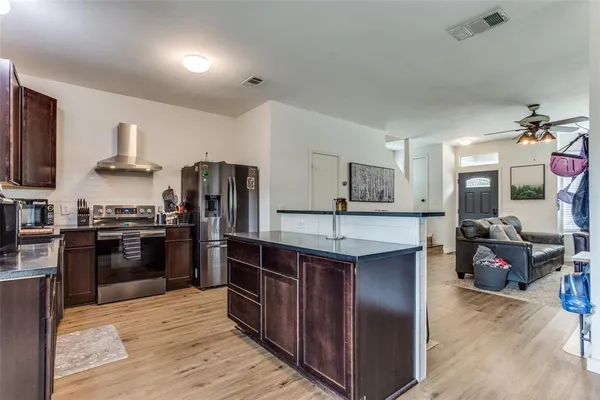 a kitchen with stainless steel appliances granite countertop a refrigerator a stove top oven a sink dishwasher and wooden cabinets with wooden floor