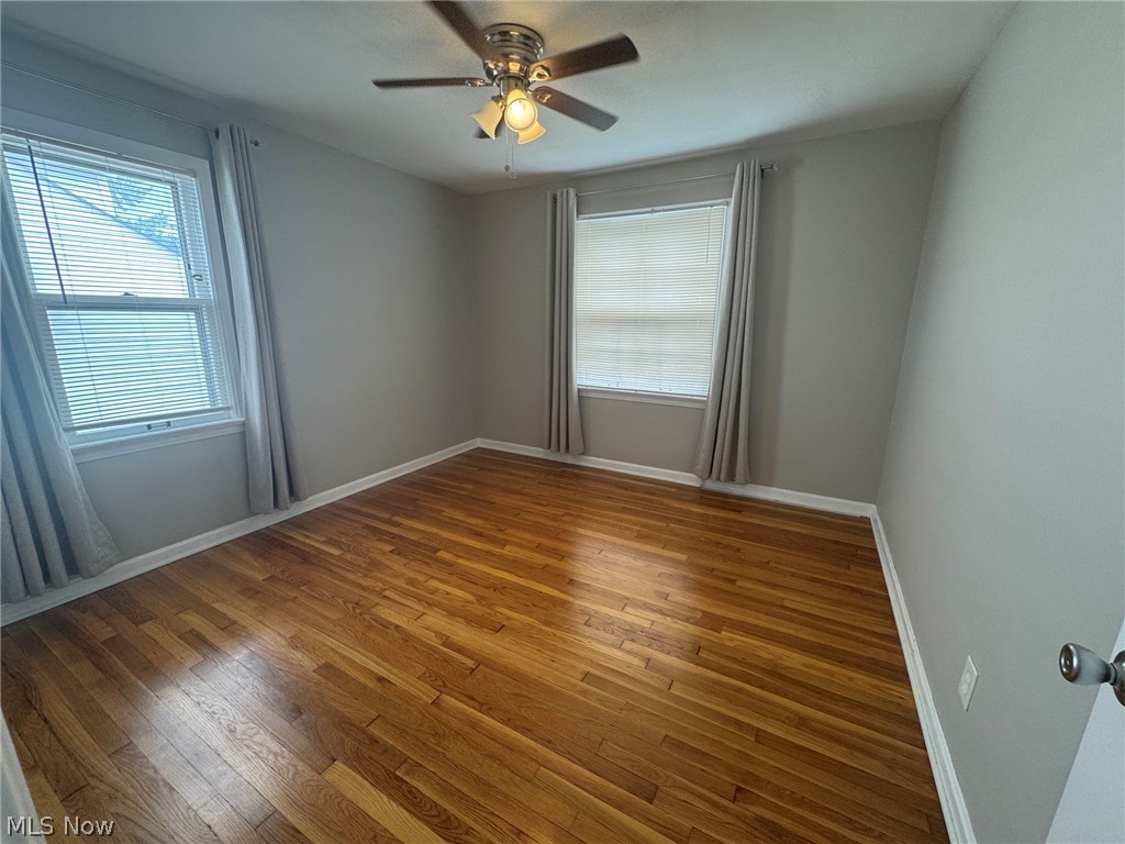 1132 Gordon Road Cleveland, OH 44124 - Photo 22 of 28 Hardwood flooring, two windows with blinds, ceiling fan with light fixture, and neutral wall tones