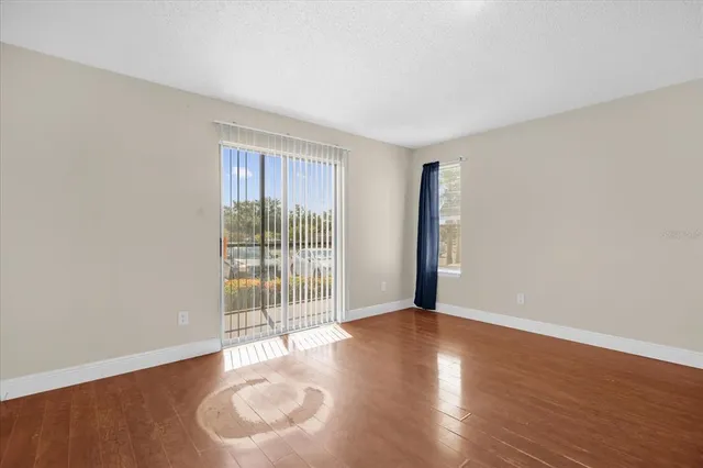 a view of an empty room with wooden floor and a window