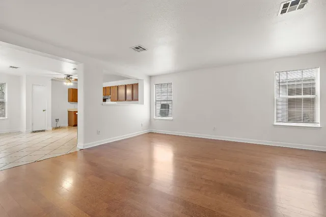 an empty room with wooden floor and windows