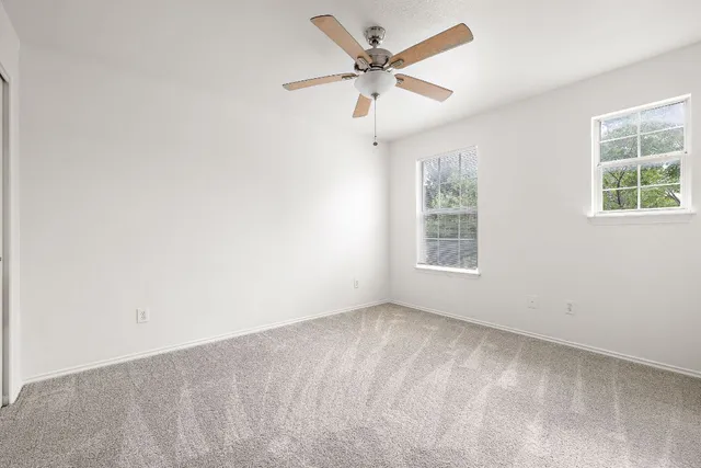 an empty room with a window and a fan