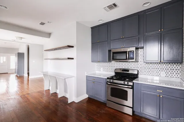 a kitchen with granite countertop a stove a sink and a refrigerator