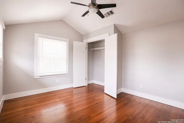 a view of empty room with wooden floor and ceiling fan