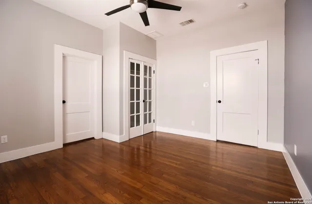 an empty room with wooden floor closet and windows