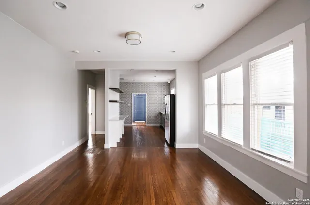 a view of a hallway with wooden floor and windows