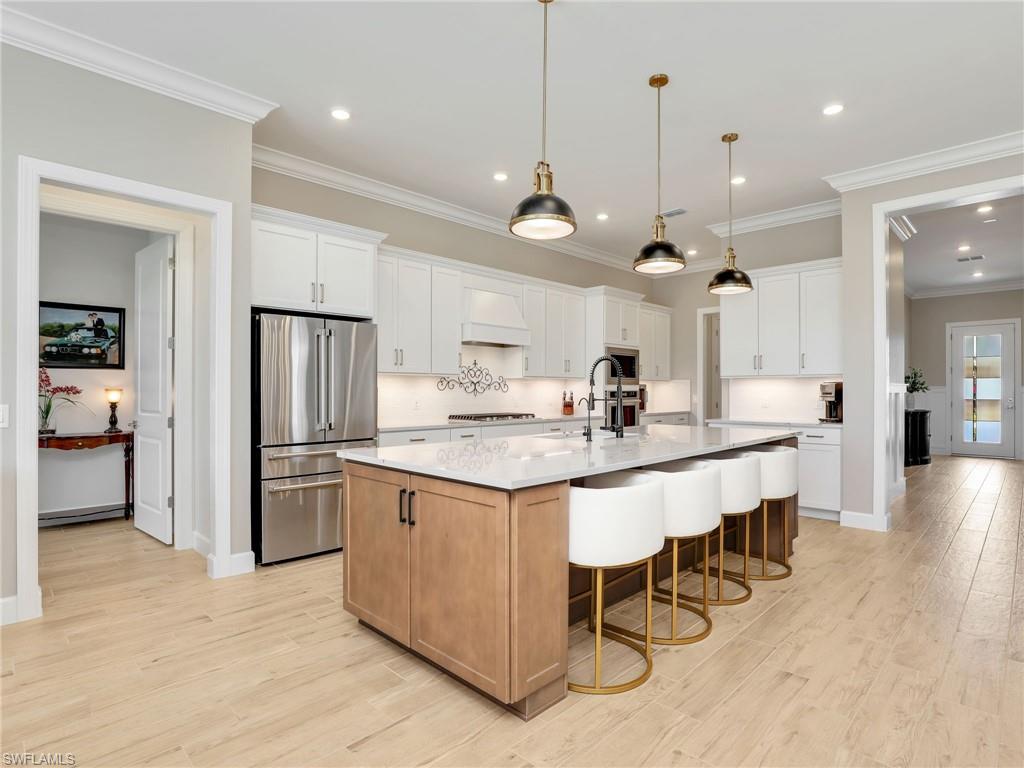 18412 Ridgeline Drive Estero, FL 33928 - Photo 13 of 50 a kitchen with stainless steel appliances granite countertop a sink a stove a refrigerator and island with wooden floor