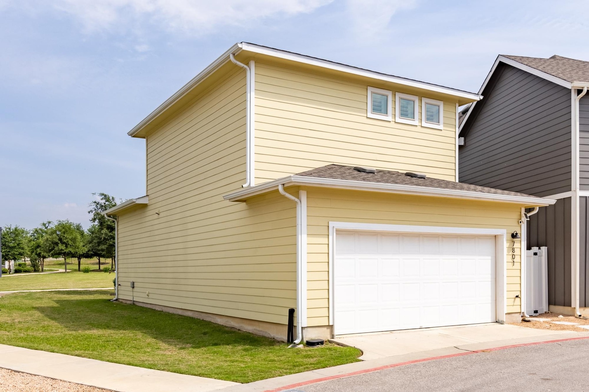 7801 Frida Bend Austin, TX 78744 - Photo 23 of 26 Yellow siding adorns this contemporary residence with an attached garage, offering practical living.