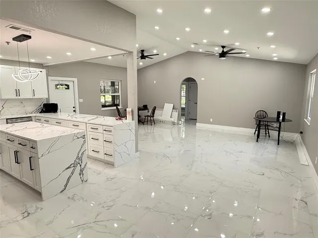 a large white kitchen with a stove a table and chair