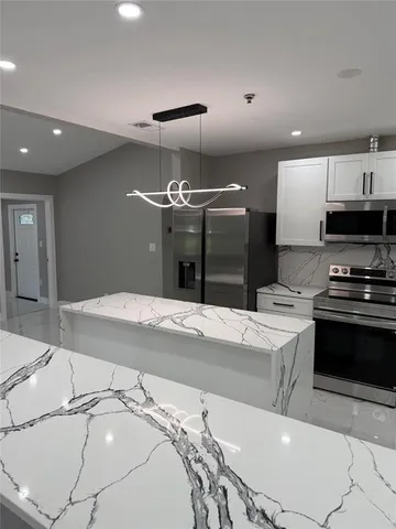 a kitchen with stainless steel appliances kitchen island granite countertop a sink and a stove