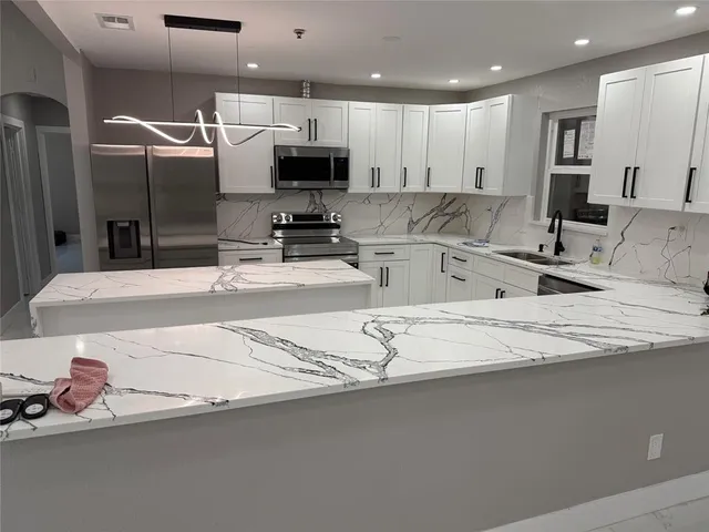 a kitchen with kitchen island granite countertop a sink a stove and cabinets
