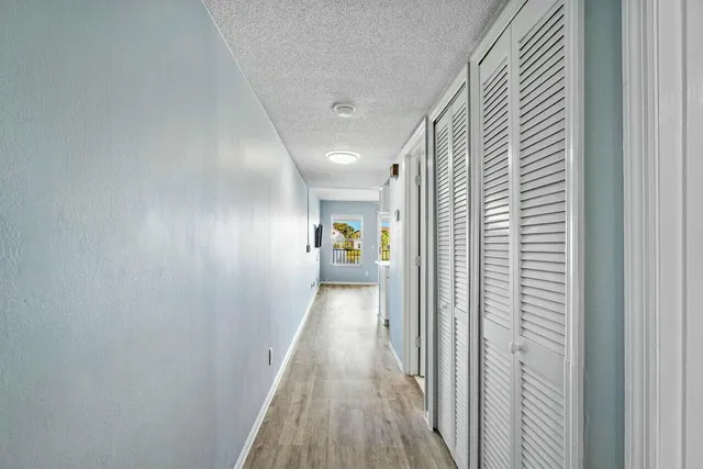 a view of a hallway to a livingroom with wooden floor and stairs