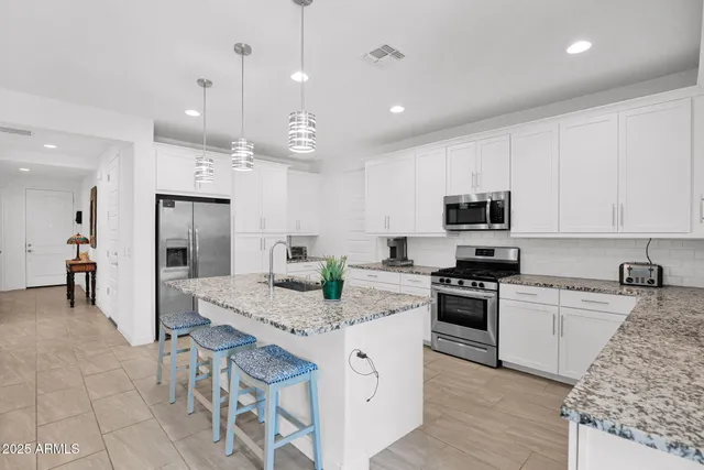 a large kitchen with granite countertop lots of counter top space appliances and cabinets