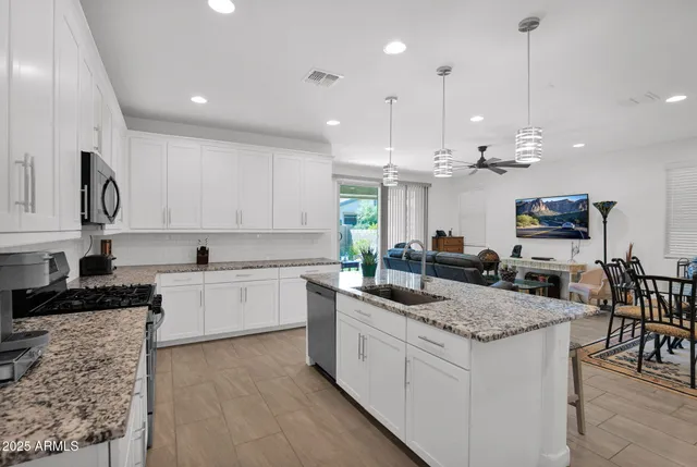 a kitchen with granite countertop kitchen island sink stove and white cabinets