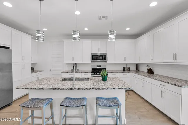 a large kitchen with kitchen island granite countertop a table chairs sink and cabinets