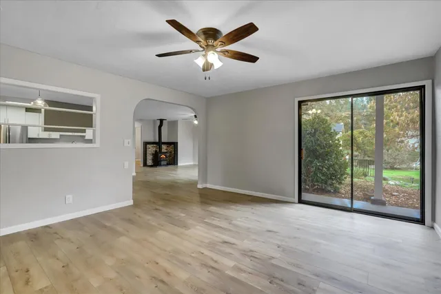 an empty room with a chandelier fan and windows
