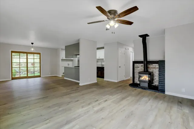 an empty room with wooden floor chandelier fan and windows