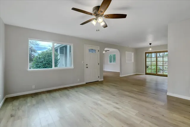 an empty room with wooden floor and windows